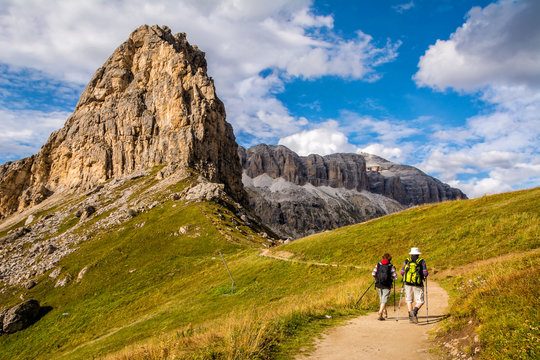 Active Senior Caucasian Couple Hiking In Mountains With Backpacks, Enjoying Their Adventure. Location: Dolomites Alps, South Tyrol, Italy, Europe.