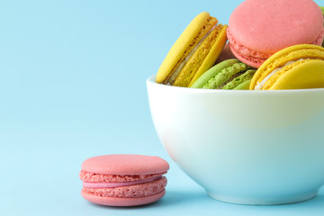 Macarons. french multicolored macaroons cakes in a cup. small french sweet cake on bright blue background. Dessert. Sweets.