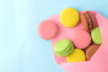 Fototapeta na wymiar Macarons. french multicolored macaroons cakes in envelope. small french sweet cake on bright blue background. Dessert. Sweets. top view.