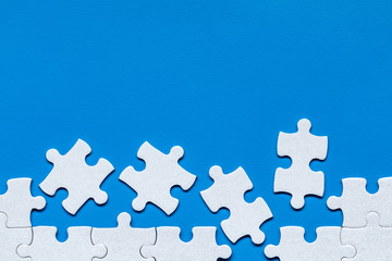 White jigsaw puzzle. White puzzle pieces on color background. Unfinished white jigsaw puzzle pieces...