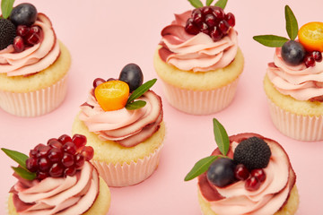 sweet cupcakes with fruits and berries on pink surface