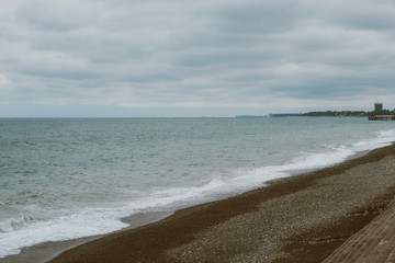 Deserted, empty sandy beach, grey sky and clouds, autumn storm.