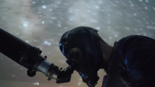 Alien looking man with mask using telescope to look at night sky, funny or creepy