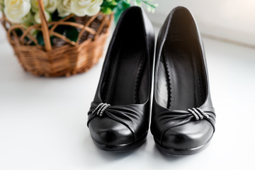 Beautiful classic vintage woman's black leather shoes with high heel on white background with flowers.