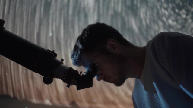 Amateur astronomer using telescope optics at night to look at gleaming sky stars