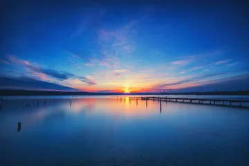 Fototapeten Small Dock and Boat at the lake. Beautiful sunset shot. © ValentinValkov