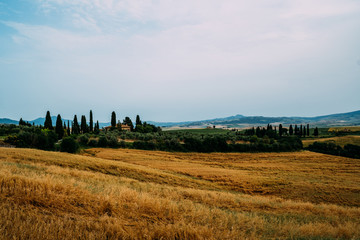 Tuscany, rural sunset landscape. Countryside farm, cypresses trees, fields, sun light and cloud. Italy. Agro tour of Europe. Holiday outdoor vacation trip.