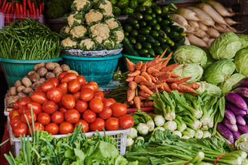 Asian food ingredients corner. Organic fresh agricultural product at farmer market. Fresh tomatoes, onions, eggplant, are packaged in simple containers and displayed for sale at an produce stand.