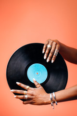 Female hands holding a vinyl record against a copper orange background