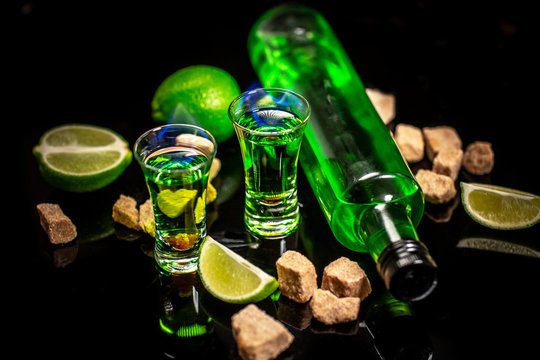 absinthe shots with sugar cubes. absinthe poured into a glass. bottle of absinthe with brown sugar and lime isolated on black background. space for text