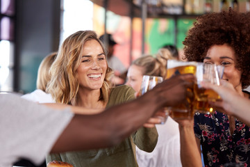Group Of Young Friends Meeting For Drinks And Food Making A Toast In Restaurant