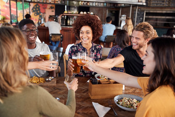 Group Of Young Friends Meeting For Drinks And Food Making A Toast In Restaurant