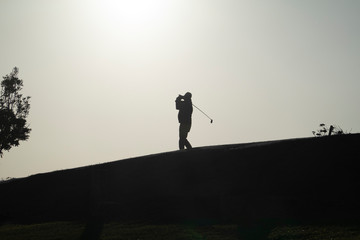golfista a contraluz golpeando una bola de golf ó golfista al atardecer o silueta de golfista al...