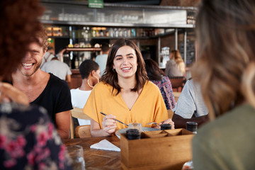 Group Of Young Friends Meeting For Drinks And Food In Restaurant