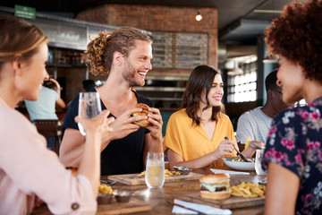 Group Of Young Friends Meeting For Drinks And Food In Restaurant