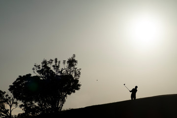 golfista a contraluz golpeando una bola de golf ó golfista al atardecer o silueta de golfista al atardecer 