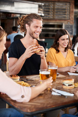 Group Of Young Friends Meeting For Drinks And Food In Restaurant