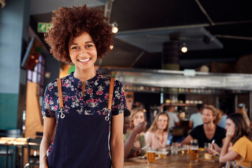 Portrait Of Waitress Serving In Busy Bar Restaurant