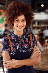 Portrait Of Waitress Serving In Busy Bar Restaurant