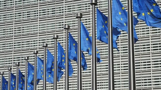 Line of impressive EU flags fluttering at EC building in Brussels in spring in slo-mo 