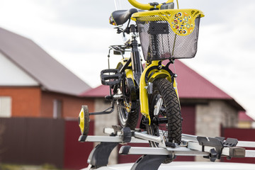 Bicycle transportation - a children's bicycle on the roof of a car against the sky in a special mount for cycling. The decision to transport large loads and travel by car