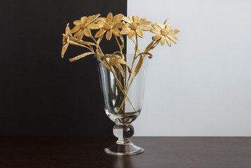 A glass vase with a bouquet of flowers made from straw on a black-and-white background