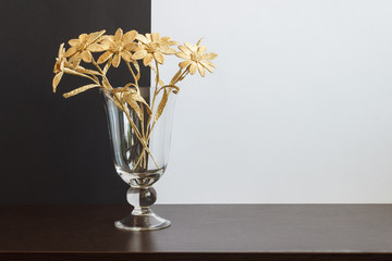 A glass vase with a bouquet of flowers made from straw on a black-and-white background. Copy space