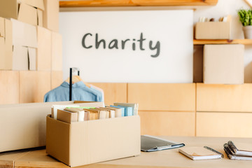 selective focus of carton box with books and placard with charity inscription