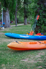 Two kayaks parked by the river with their oars on the grass. Horizontal