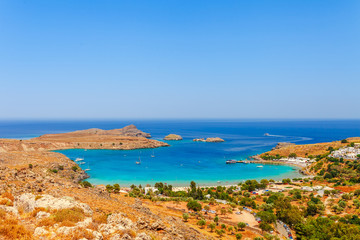 Fototapeta na wymiar Sea skyview landscape photo Lindos bay and castle on Rhodes island, Dodecanese, Greece. Panorama with ancient castle and clear blue water. Famous tourist destination in South Europe