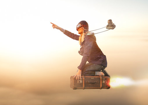 Mutige Entdeckerin fliegt auf Ihrem Koffer Richtung Sonnenaufgang in den Urlaub