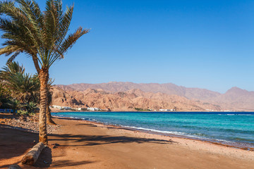 Sunny resort beach at the coast shore of Red Sea in Dahab, Sinai, Egypt, Asia in summer hot. Famous tourist destination near of Sharm el Sheikh. Bright sunny light
