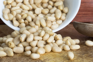 Raw pine seeds in white bowl, healthy vegetarian snack 