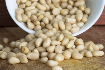 Raw pine nuts in white ceramic bowl, healthy vegetarian snack 