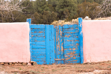 weathered blue gates with pink adobe walls © Gerald Zaffuts