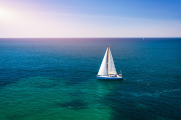 White sail boat isolated in blue sea water. Sailboat in the sea in the sunlight, luxury summer...