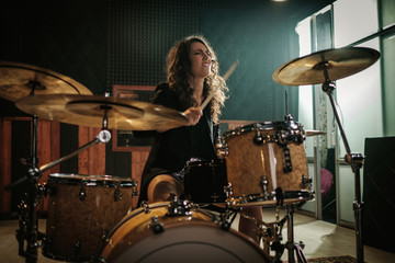 Obraz na płótnie Canvas Woman playing drums during music band rehearsal