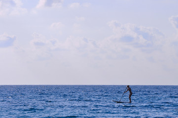 Silhouette unidentified girl stand up paddle boarding at the beach - Image holiday/vacation concept