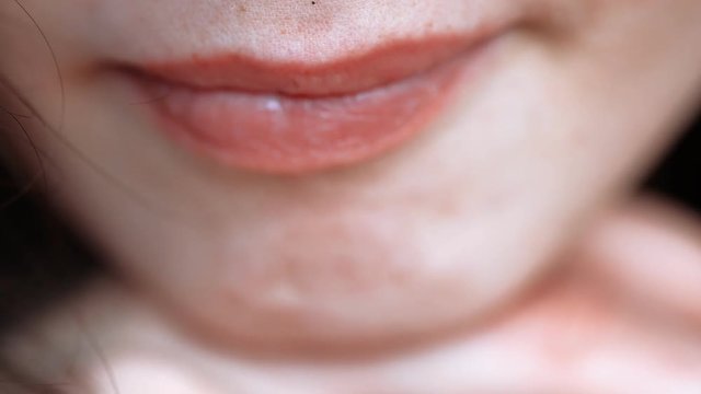 Closeup of womans coral lips, girl shows out her tongue with piercing shallow DOF