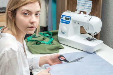 Seamstress cuts fabric. process of tailoring. Portrait of a seamstress at work close-up.