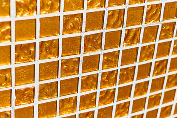 golden mosaic tile. a fragment of a wall with a mosaic of golden color