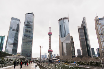 Skyscrapers of the Pudong area against cloudly sky. View from the pedestrian bridge along which people walk