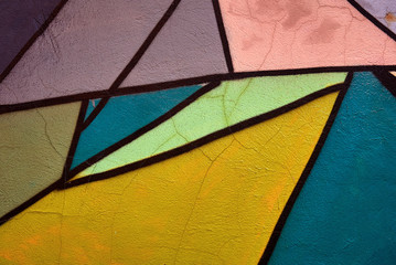 fragment of a multicolor pattern on the graffity wall with cracks and chips