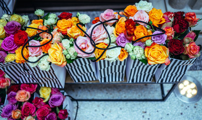 A lot of colorful roses flowers in shopping bags