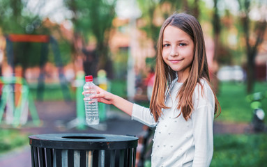 Little girl throwing bottle into the trash. Ecology concept