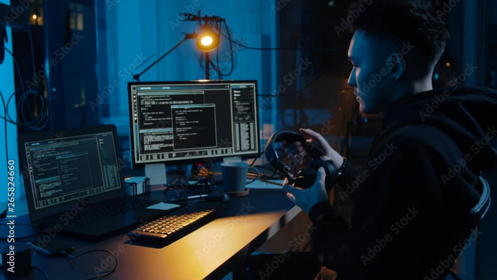 Poster cybercrime, hacking and technology concept - asian male hacker in headphones with coding on laptop c