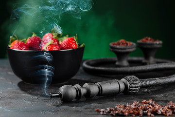 Shisha Smoking hookah in a green bowl on the background of a bowl of strawberries. Horizontal.