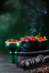 Obraz na płótnie Canvas Shisha Smoking hookah in a green bowl on the background of a bowl of strawberries. Vertical.