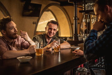 Cheerful friends drinking draft beer in a pub
