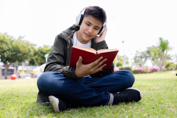 teenager boy thailand are listening to headphones music on smartphone in the park